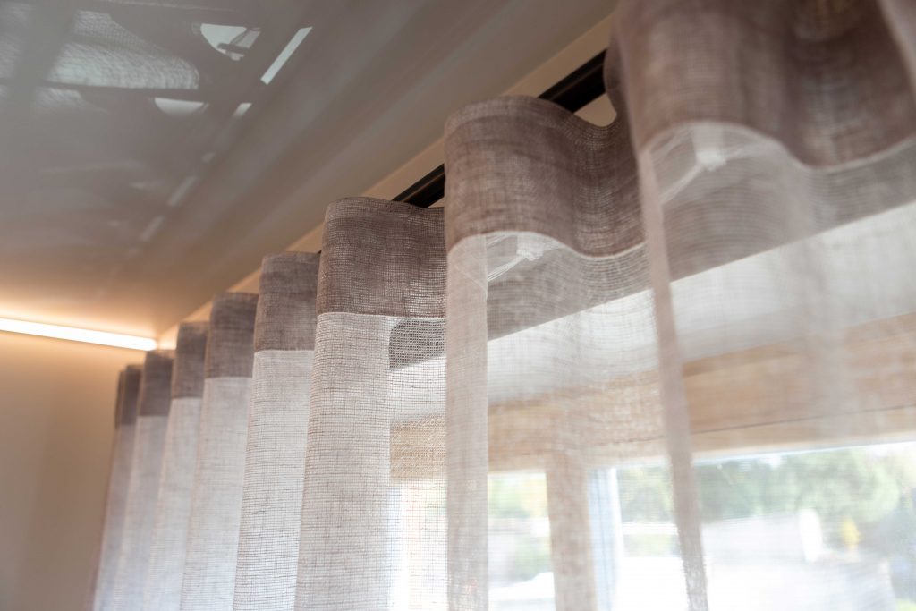 Baltos spalvos užuolaidos šviesiame interjere, suteikiančios lengvumo ir jaukumo