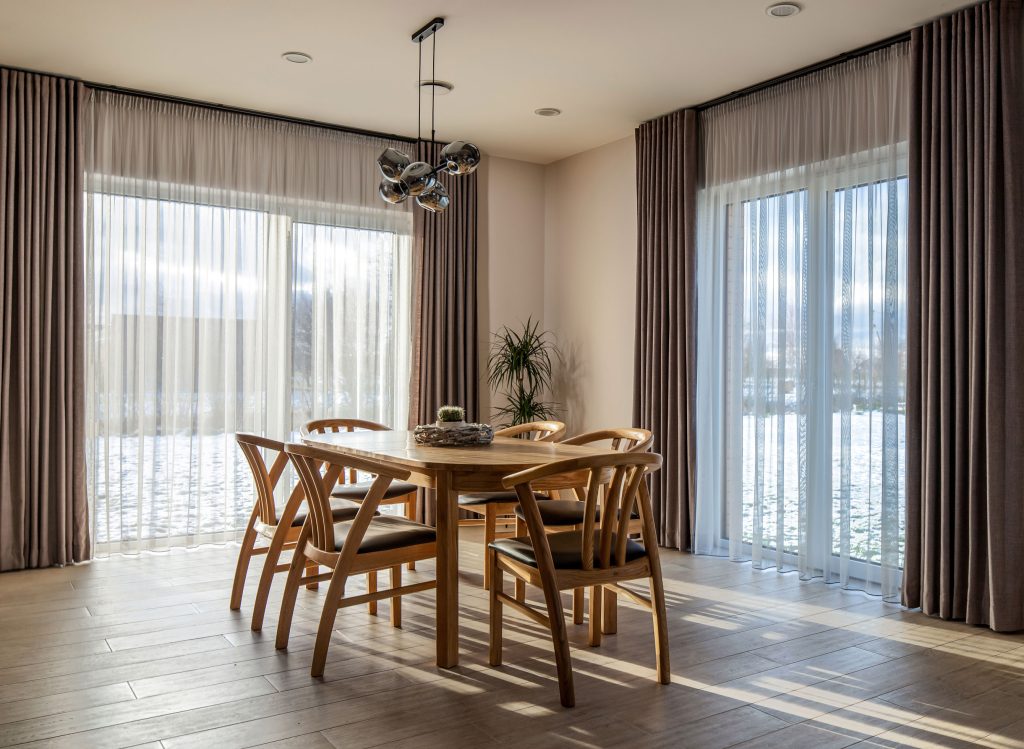 Dalinėmis klostėmis rauktos dieninės ir naktinės užuolaidos moderniame interjere