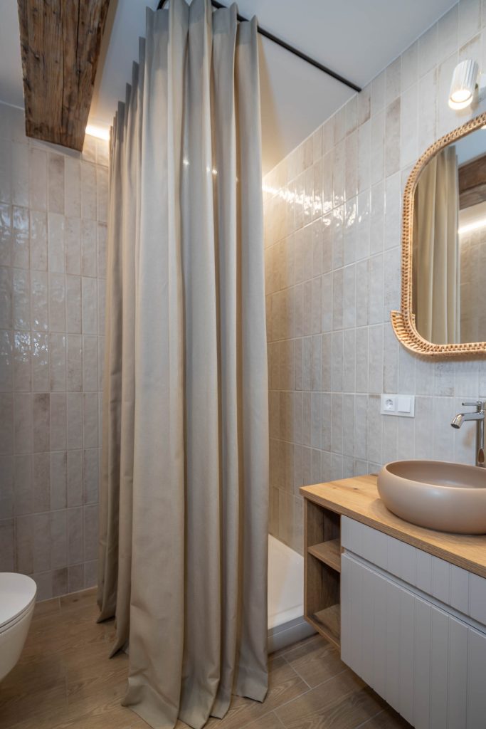 Dušo kabinos užuolaidos pakabintos ant bėgelio vonios kambario interjere