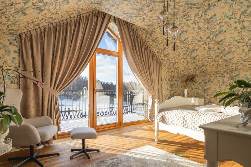 Rankiniu būdu suraukta užuolaida trikampio formos lange interjere