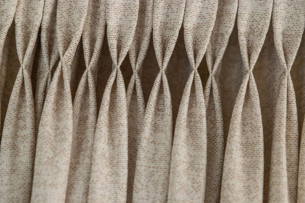 Rankiniu būdu suraukta užuolaida su formuojamomis klostėmis interjere